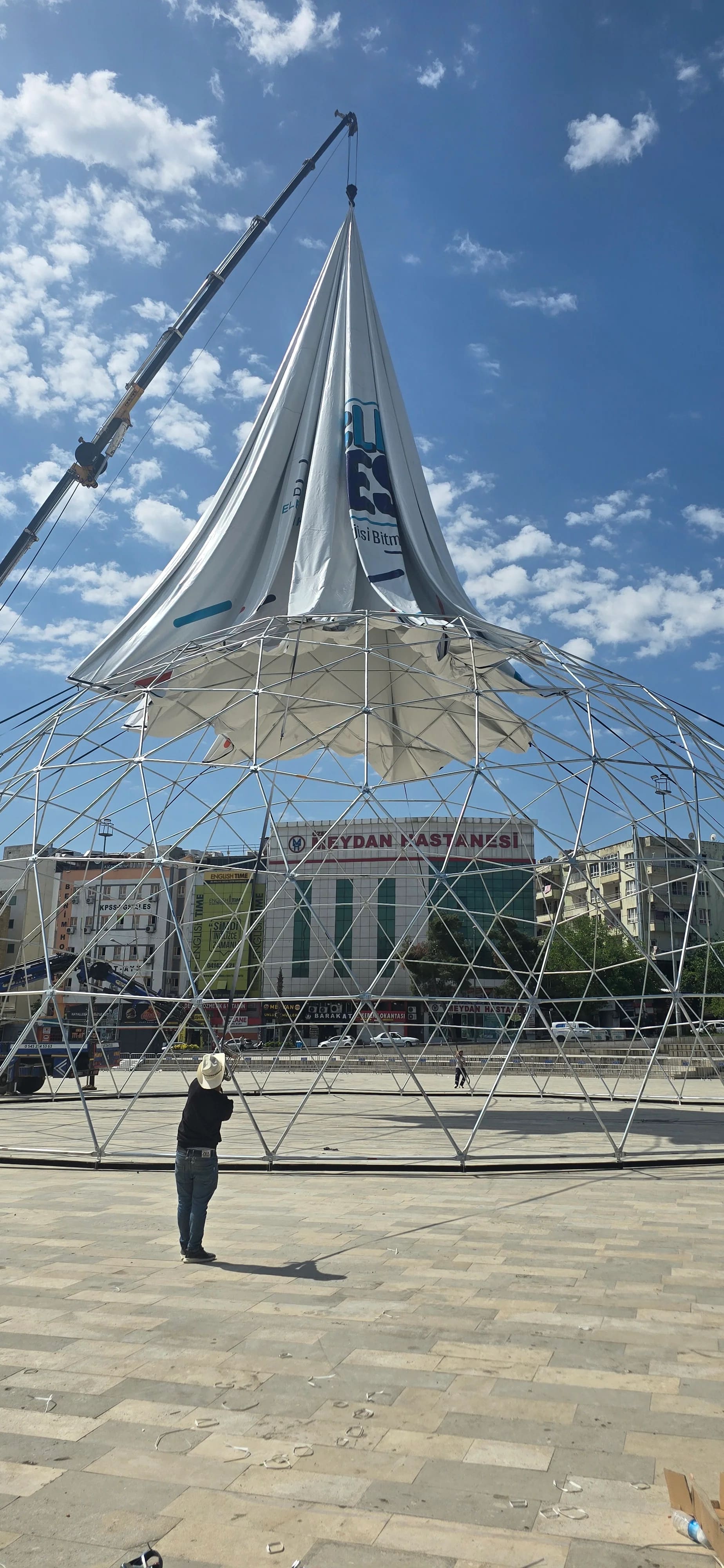 Meydanda kurulan dome çadırın geodezik iskeleti ve vinçle indirilen branda
