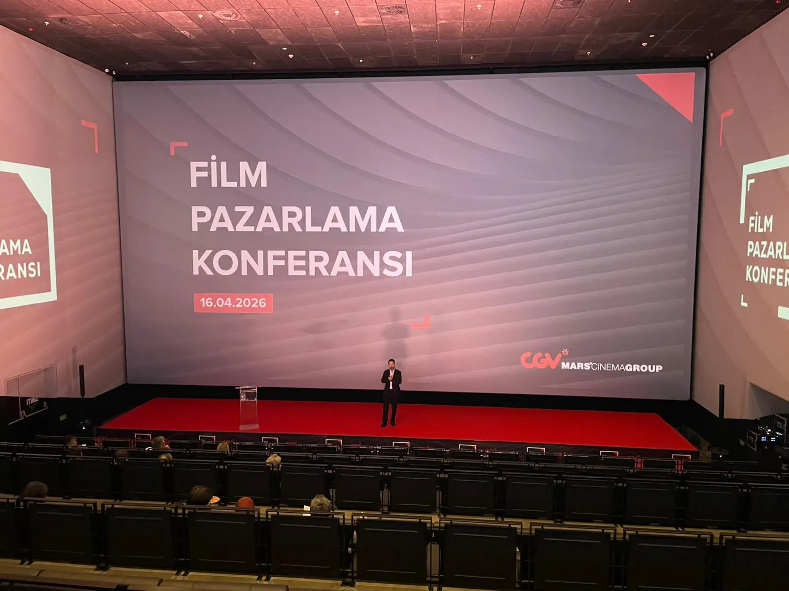 Kurumsal organizasyon türü örneği: dev perde ve sahnede konuşmacı ile konferans