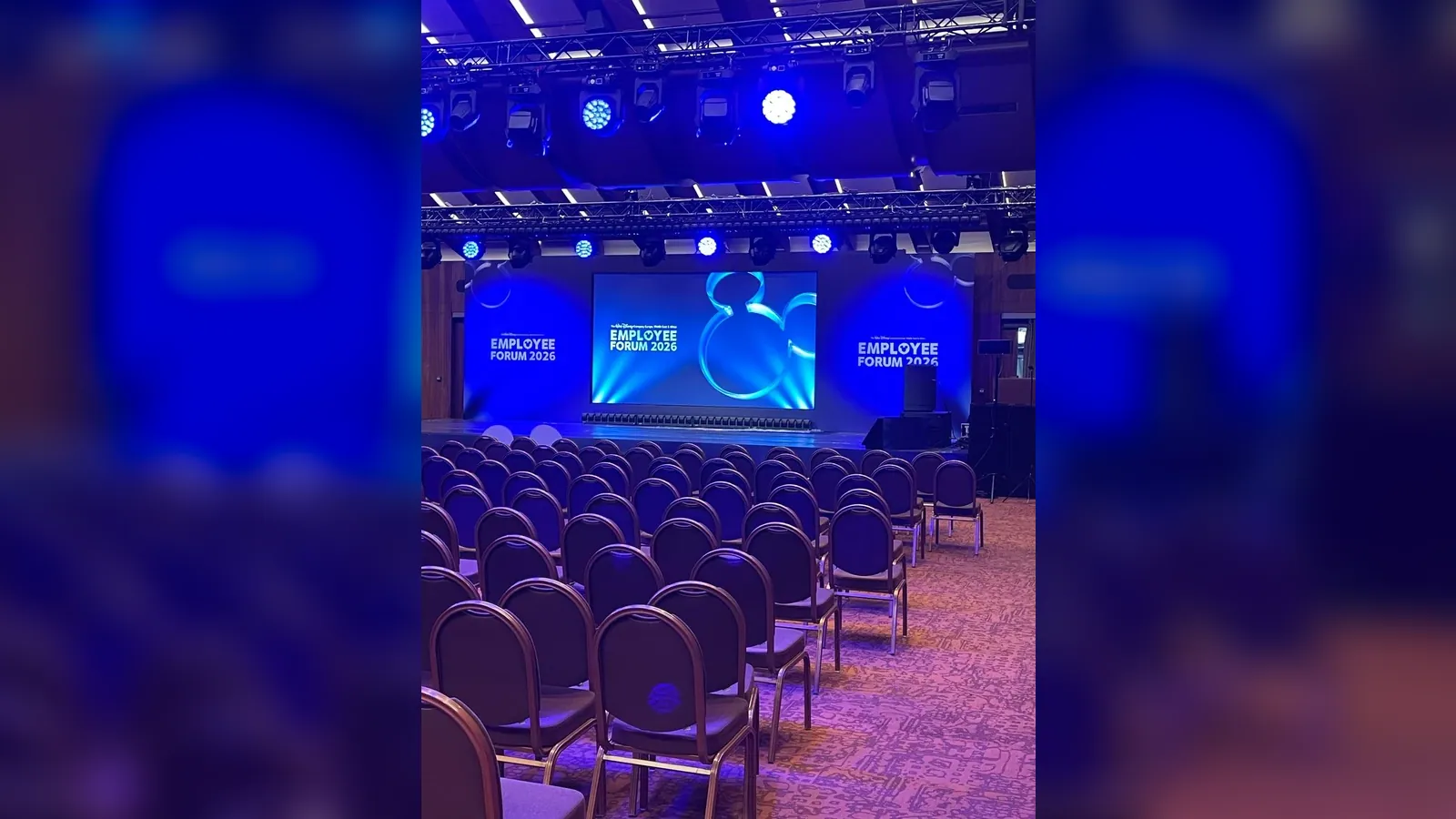 Konferans sahnesinde LED ekran, truss ve mavi ön ışık kurgusu
