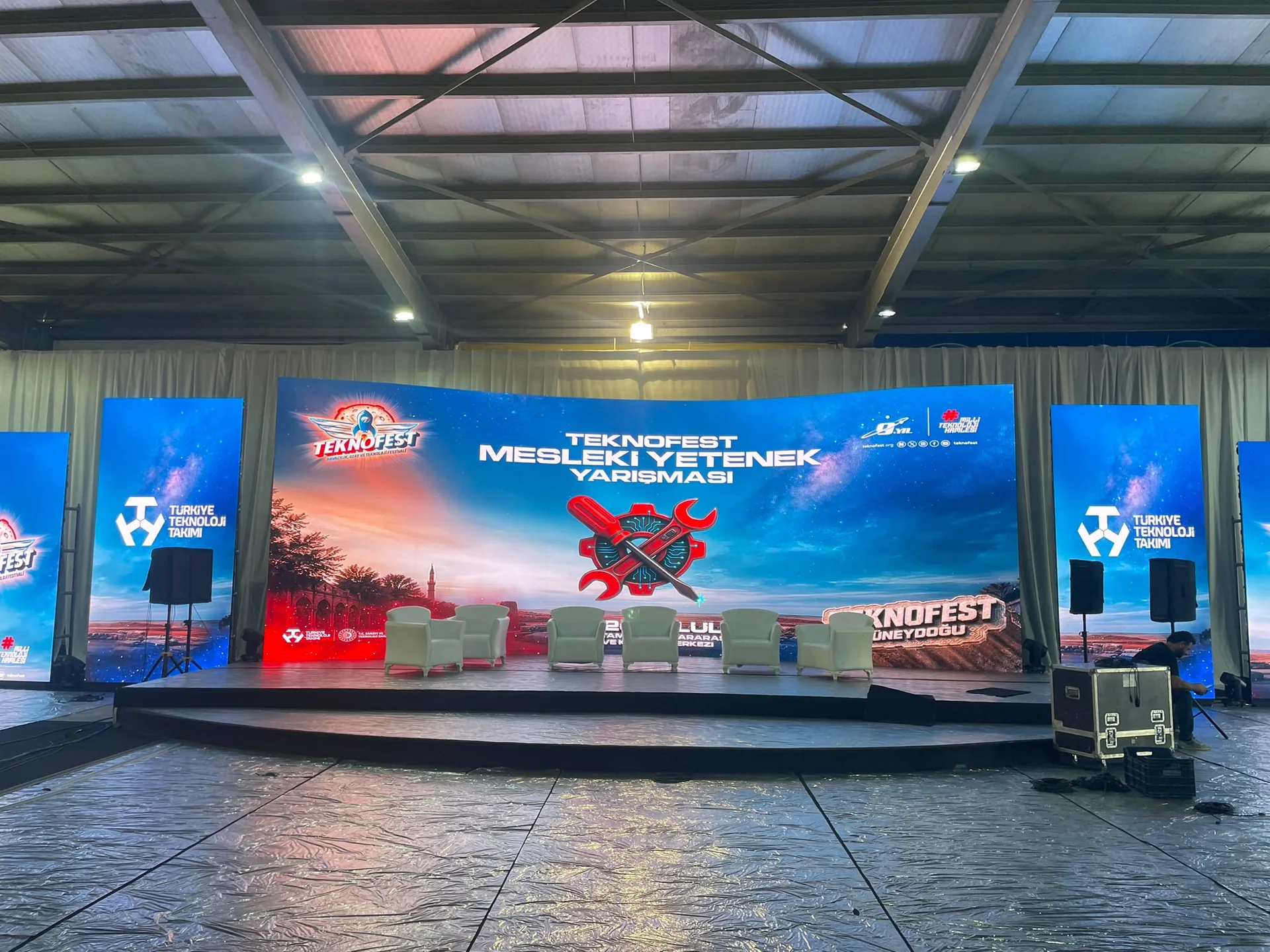TEKNOFEST Diyarbakır sahnesinin çapraz görünümünde kavisli P1.9 LED ekran, yan totemler ve hoparlör yerleşimi